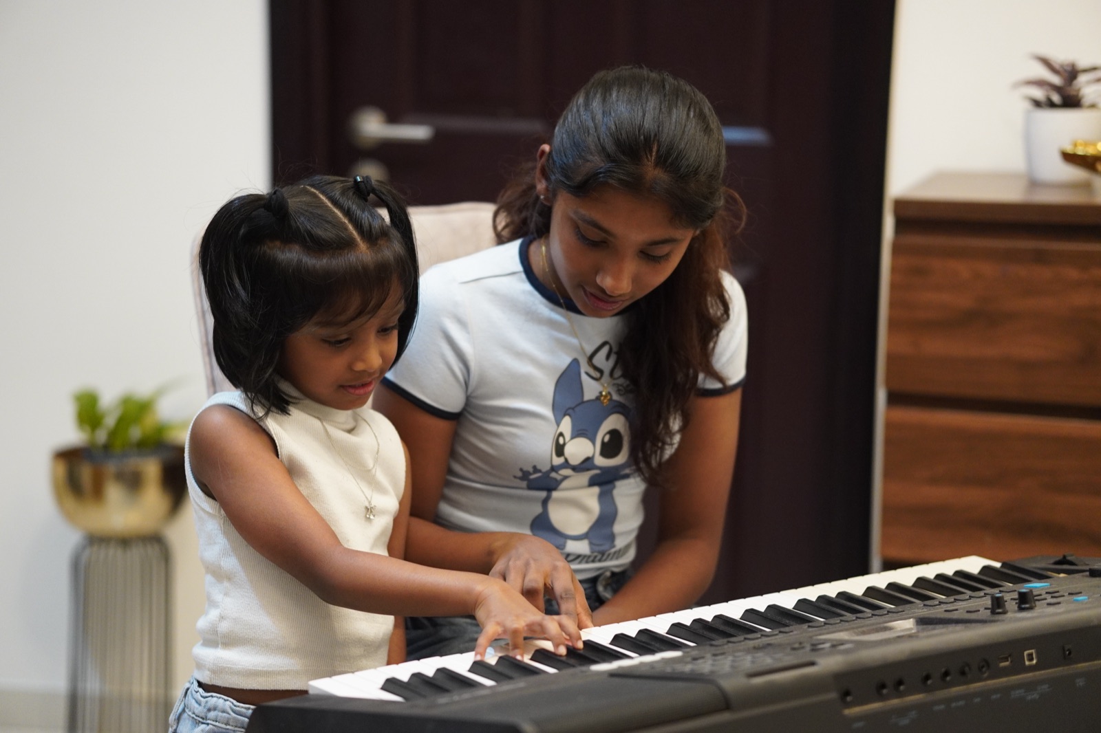 A senior student guiding a younger learner at The Clavier Studio